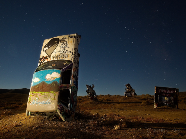 Graffiti on car stuck in the ground under the stars 