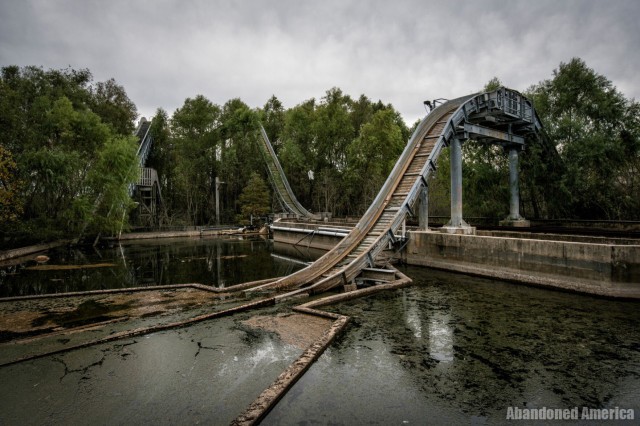 The crest of a ride track that descends into disgusting brackish water. In the background two more ramps are visible, nearly hidden by the trees